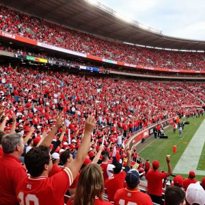 Cheering fans in a stadium wearing Kansas City Chiefs colors